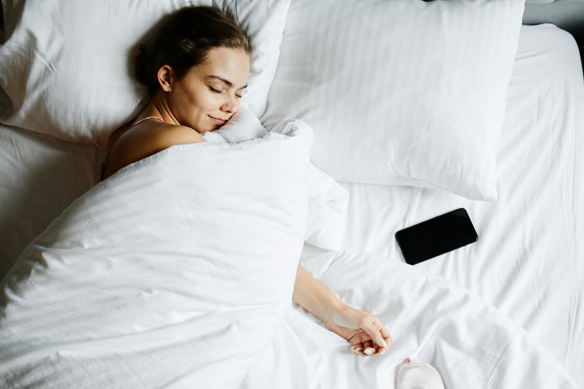 Femme endormie dans un lit aux draps blancs, illustration de l'article sur le sommeil